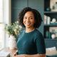 A friendly and diverse woman smiling, representing a satisfied customer in a professional and bright setting.